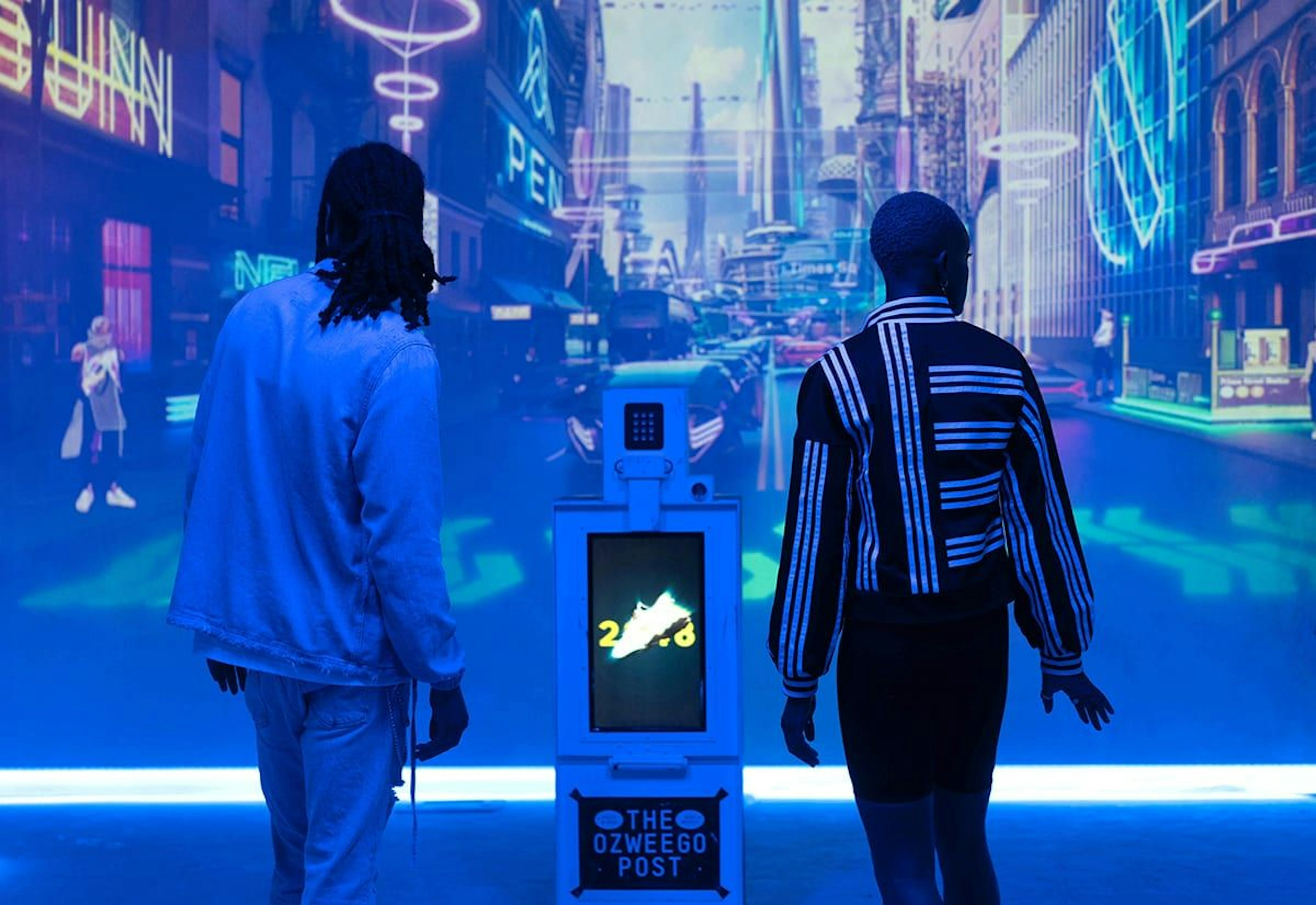Two visitors to the Adidas Ozweego experience stand in front of an immersive projection of the future.