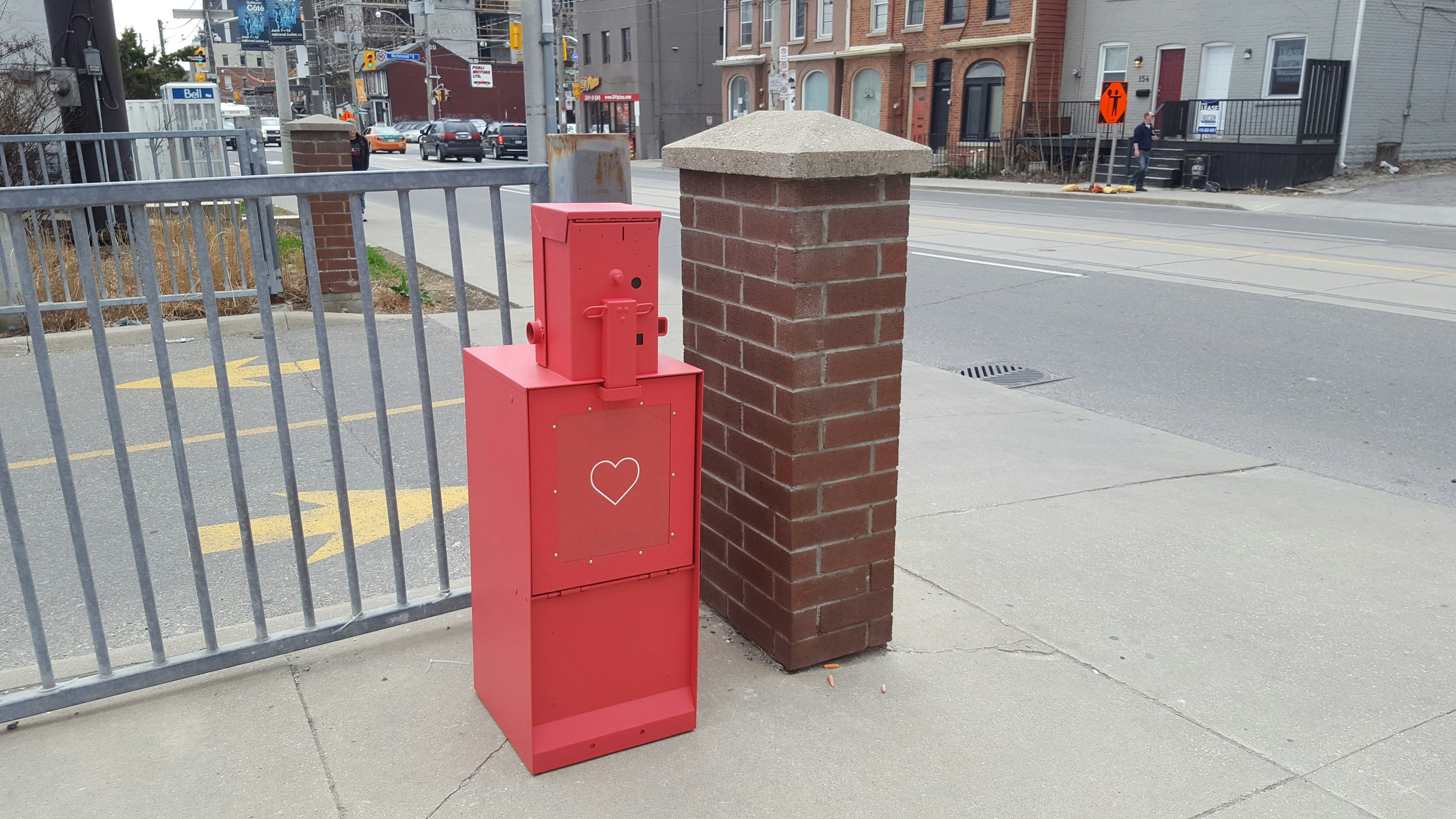 A red newspaper box sits on the street on Parliament Street in Toronto.