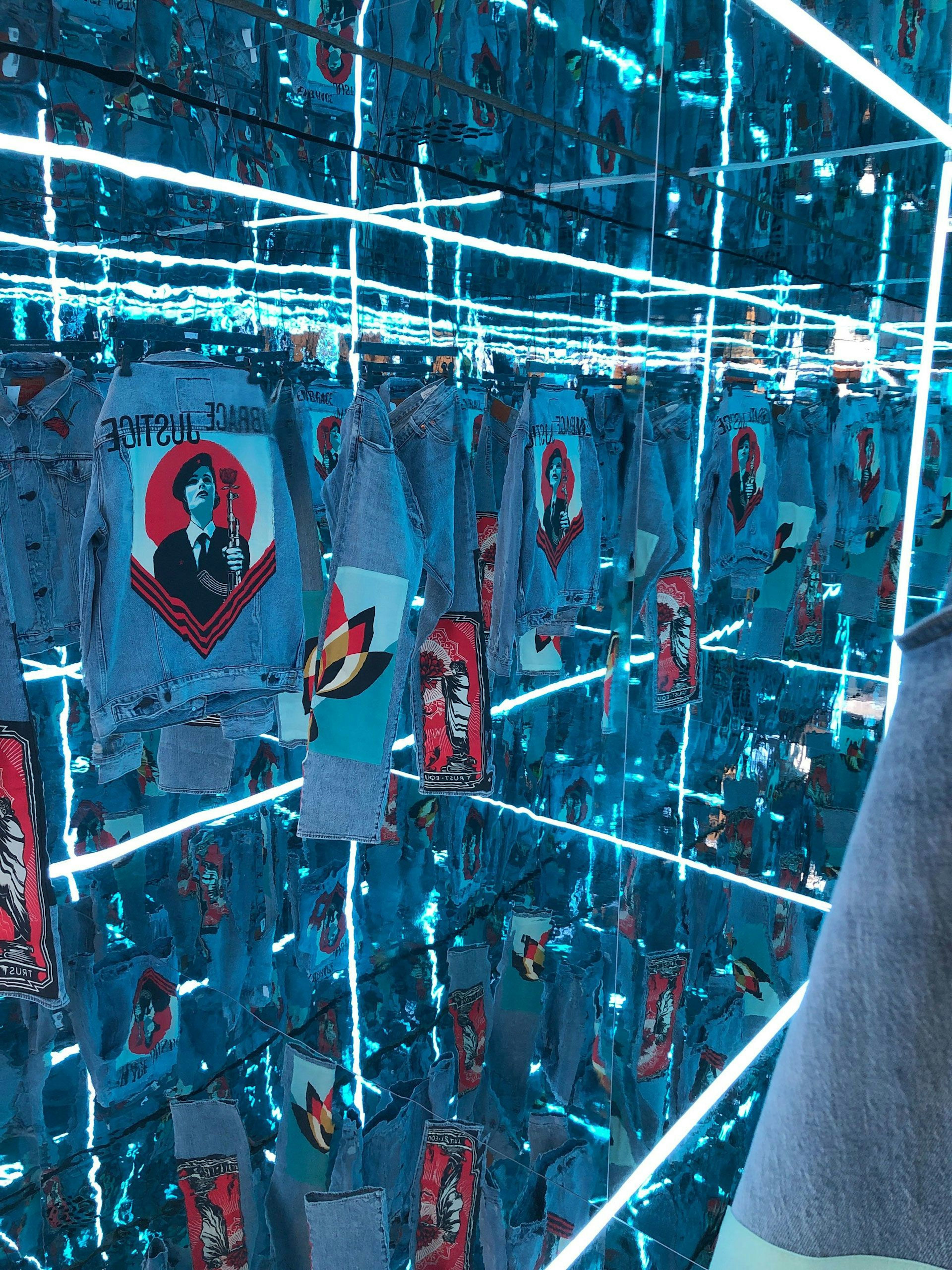 The interior of the shipping container shows an infinity room that is edge-lit with RGB LED strips. Shepherd Fairey customised clothing hangs in the space.